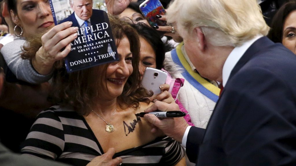 Republican presidential candidate Donald Trump (R) autographs the chest of a woman at his campaign rally in Manassas, Virginia December 2, 2015. Republican presidential front-runner Trump said on Wednesday his plan for combating Islamic State militants involves targeting not just the group's fighters but also their families. REUTERS/Gary Cameron TPX IMAGES OF THE DAY - RTX1WXC1
